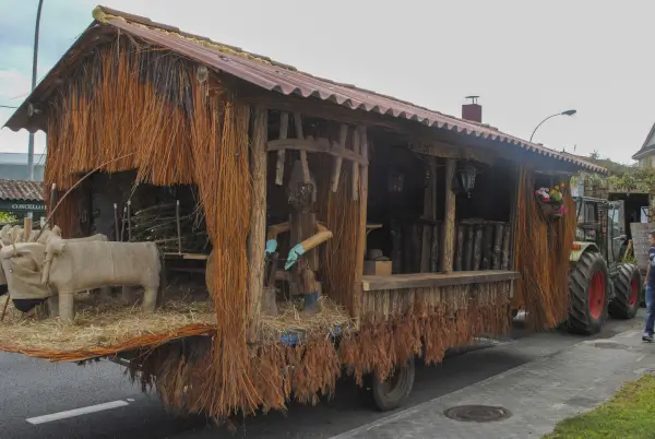 Desfile de carrozas artesanales decoradas con motivos rurales y productos gastronómicos, con gente disfrutando en la Fiesta de San Cidre en Oural.