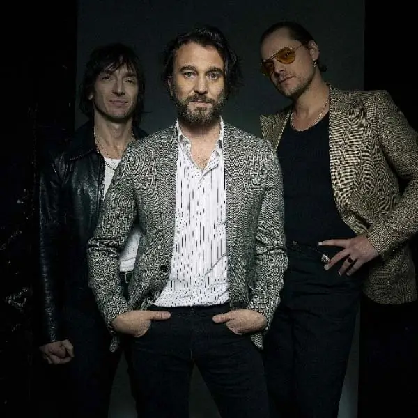 Miembros de la banda JET tocando instrumentos en el escenario.