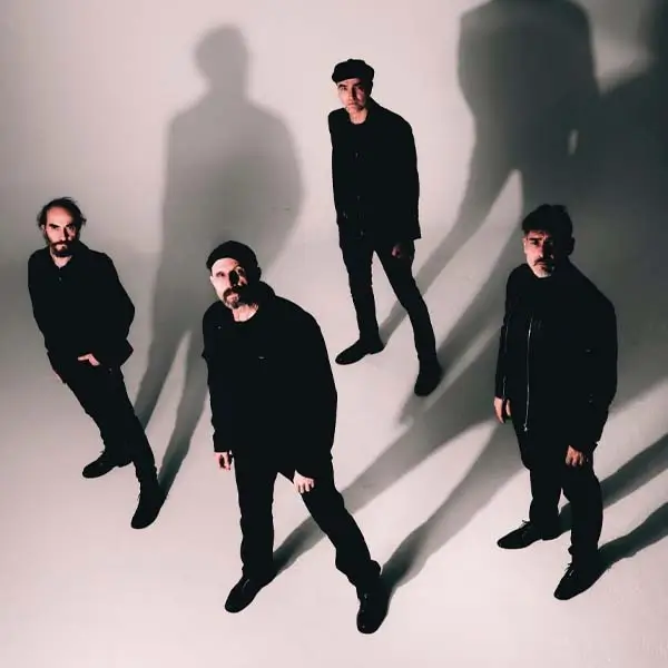 La banda de rock Los Enemigos actuando en un escenario con energía y luces de concierto, con el vocalista al frente.