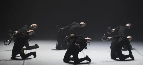 Bailarines en escena con movimientos intensos y expresivos, evocando un ritual de tarantismo con iluminación dramática.