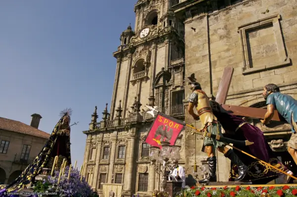 Procesión de Semana Santa en las calles históricas de Santiago de Compostela, con cofrades y pasos bajo la luz de las farolas.