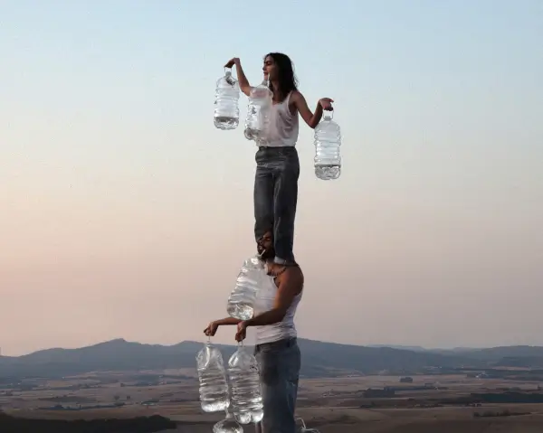 Escena de danza contemporánea '52-BLAU' con varios bailarines en movimiento en un espacio no convencional, uno de ellos suspendido.
