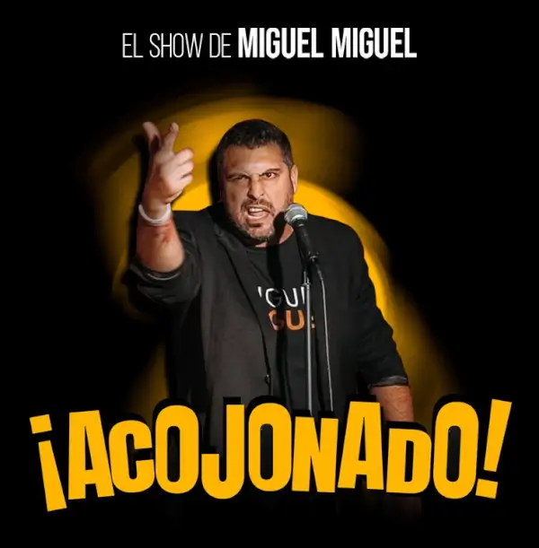 Miguel Miguel en el escenario, realizando un monólogo de comedia con un micrófono y gestos expresivos.