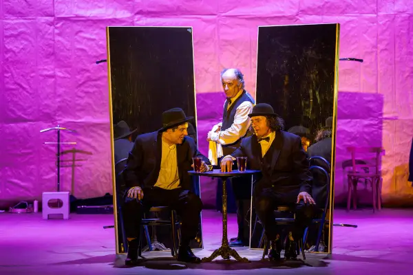 Tres actores caracterizados como payasos en el escenario de 'Mofa&Befa: Os dous de sempre', con una escenografía sencilla y luces teatrales.
