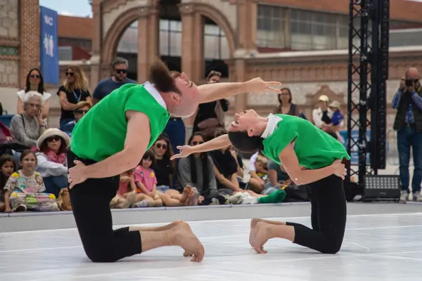 Dos bailarines en un escenario al aire libre, con movimientos que evocan un viaje a través de la vida y la memoria.