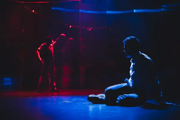 Escena de la obra 'Xoguetes rotos' con dos actores en un ambiente que evoca el Vigo industrial de los años 70, con luces tenues.