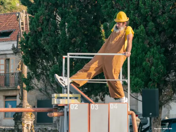 Un artista de circo realizando acrobacias en un escenario que simula una fábrica antigua con engranajes y maquinaria oxidada.